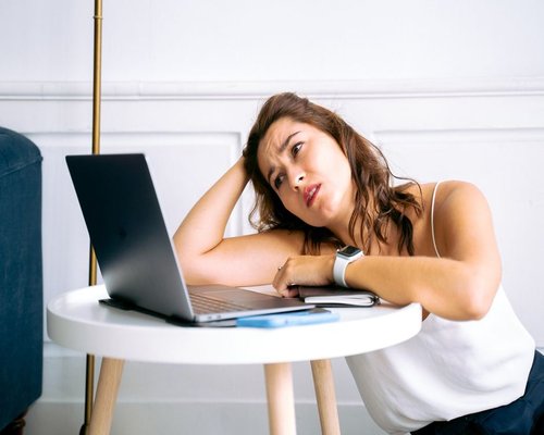 Person resting eyes by looking away from laptop monitor in a bright office